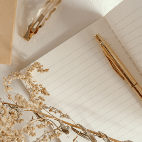 Vue de haut d'un carnet de note avec un stylo doré brillant posé dessus