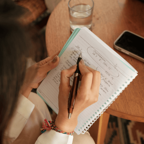 Vue de haut d'une femme écrivant sur un cahier des notes