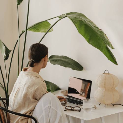 Une jeune femme de dos assise devant son ordinateur portable